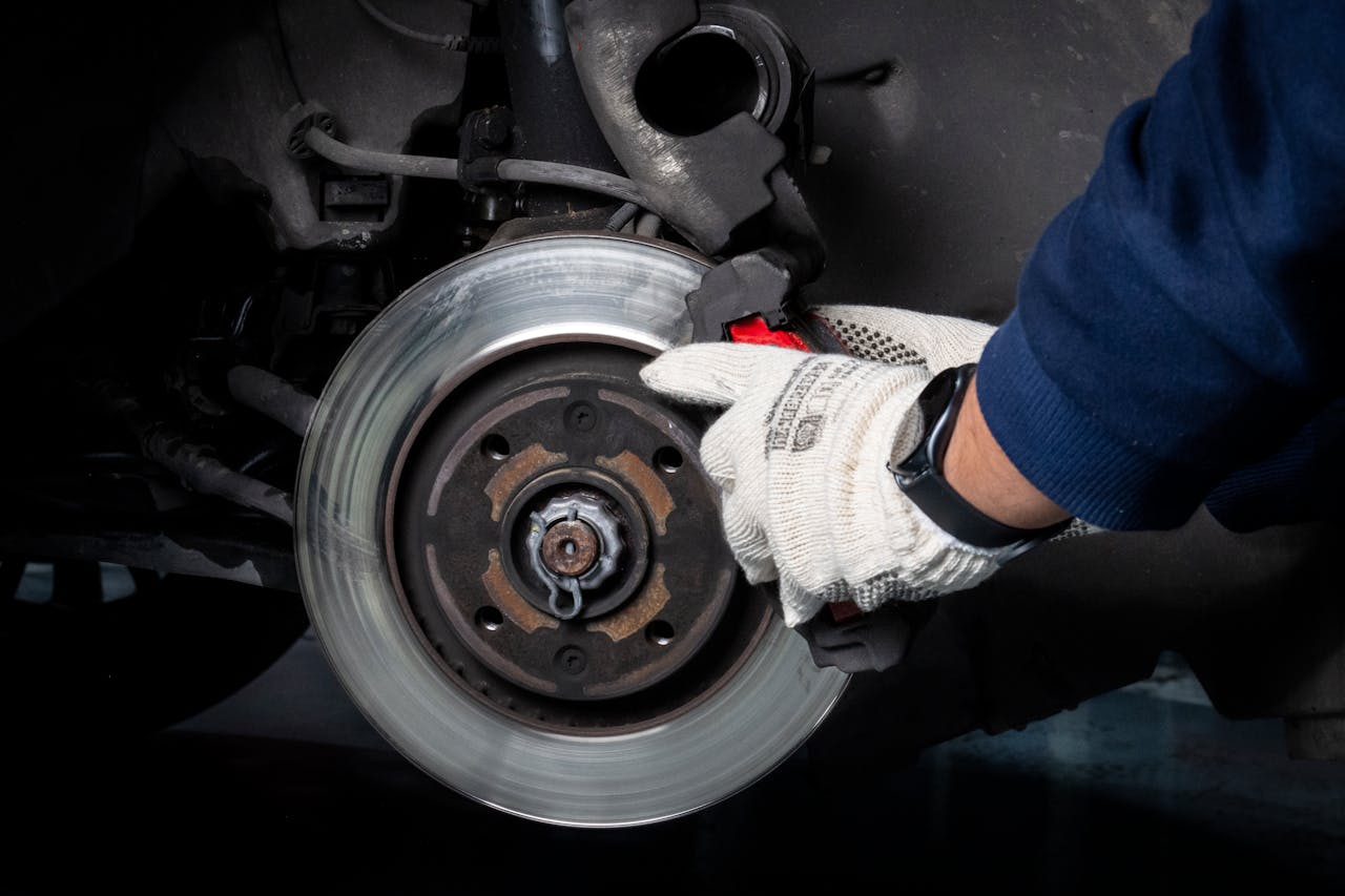 services-01 Mechanic working on car brake system in a workshop setting.