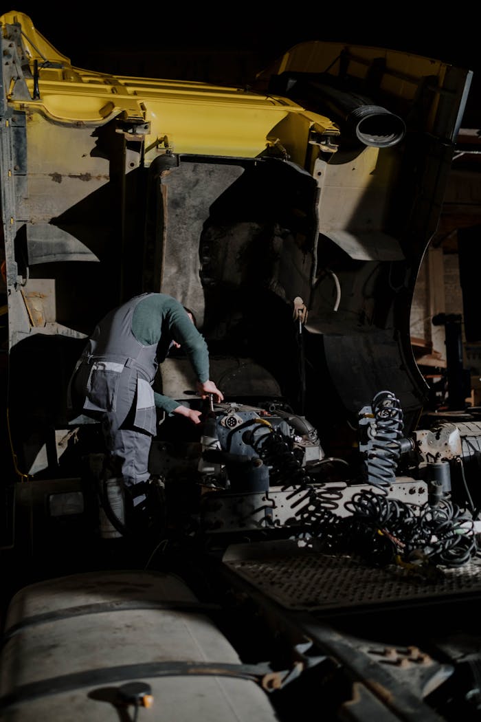gallery-06 Mechanic working on a truck engine repair at night in a dimly lit garage.