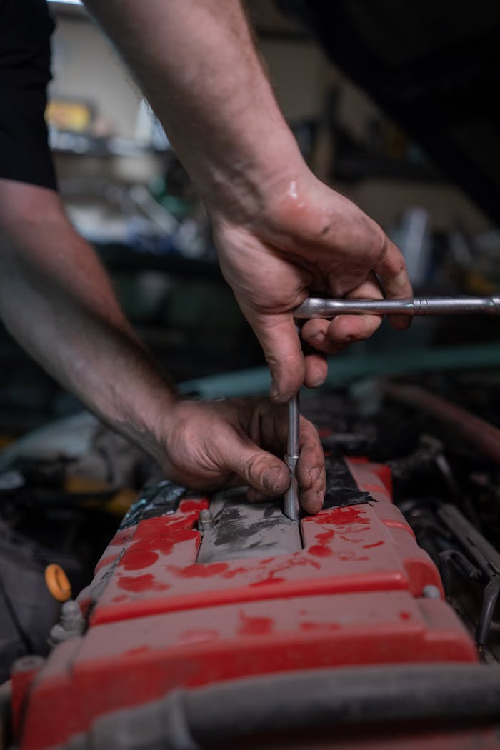 gallery-02 A mechanic uses a socket wrench to repair a car engine in a garage setting.